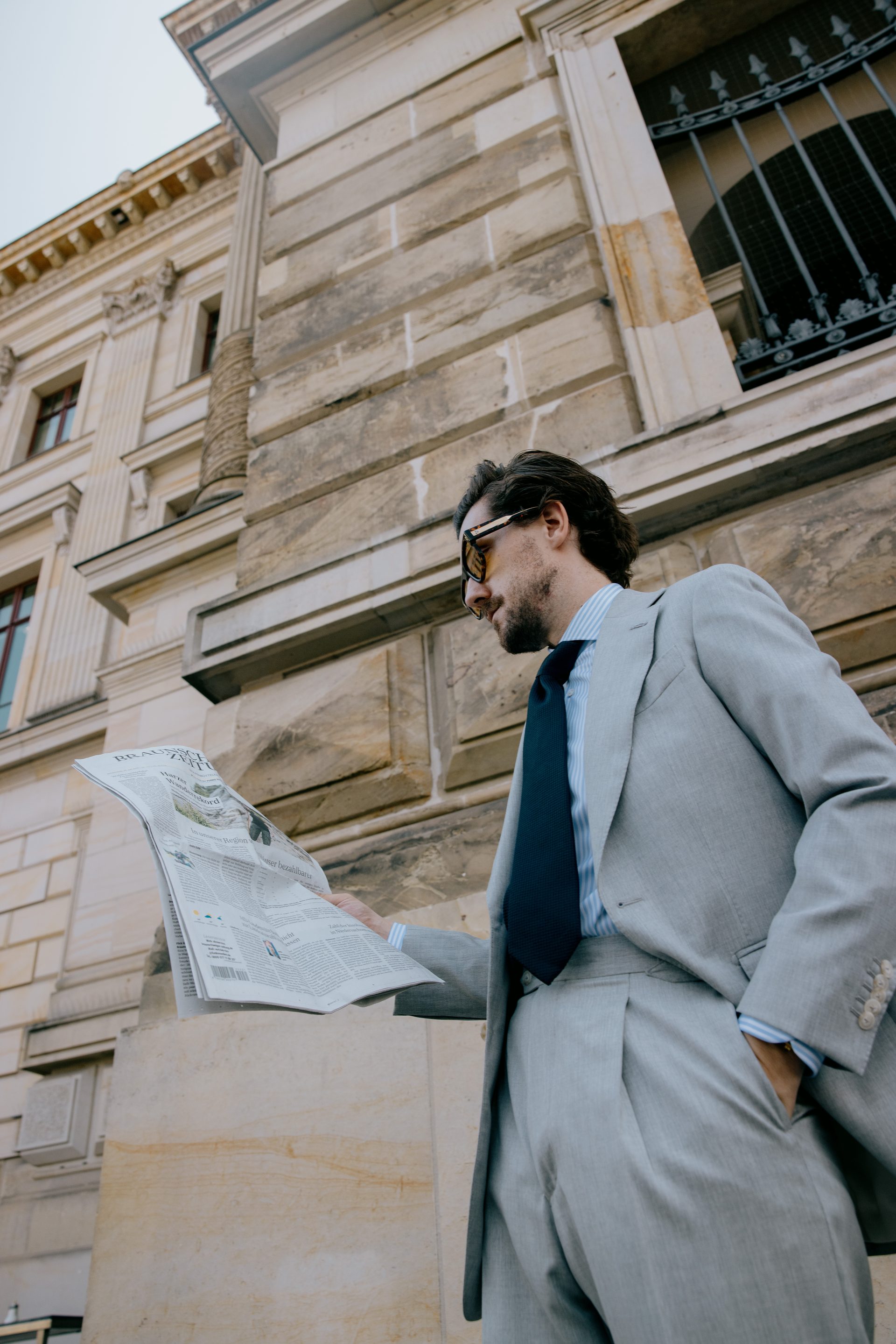 Urban Menswear mit Tageszeitung vor Berliner Architektur